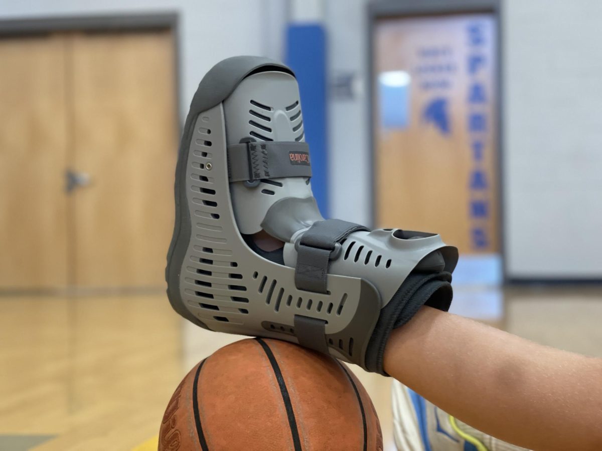 A CSD spring sports athlete wears a walking boot due to an overuse injury. Injuries can be tough for an athlete, especially at the high school level, but coming back strong is how a team can bounce back. Longing for the court, field, track, etc. will happen through a successful rehab. (CSD Journalism class photo.)