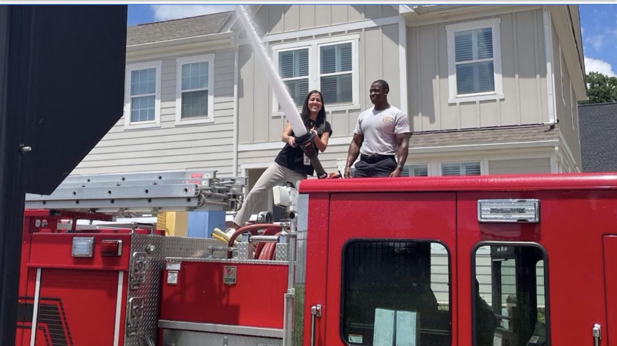Math teacher, Gurpreet ‘Guppi’ Berger, stands atop the Davidson Fire Department’s Engine 1 during Spartan Day 2023. She uses the fire hose to spray students with water on the Community School of Davidson field during the outdoor activities.
