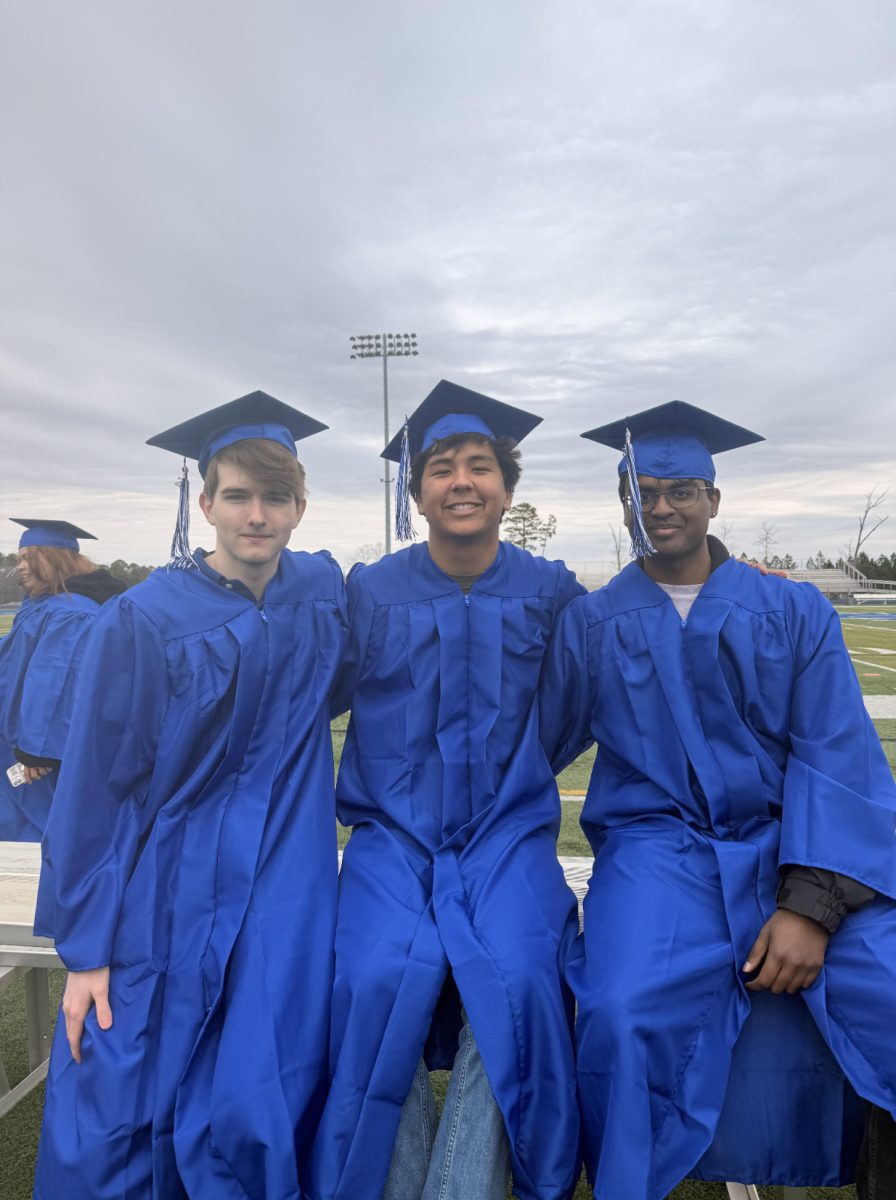 Maxwell Shealy, Liam Hogan, Akhilan Kumaran (all ‘26) ordered from left to right, sit on the Spartan Park field during graduation pictures. (Photo by Bailey Rowles (‘26))
