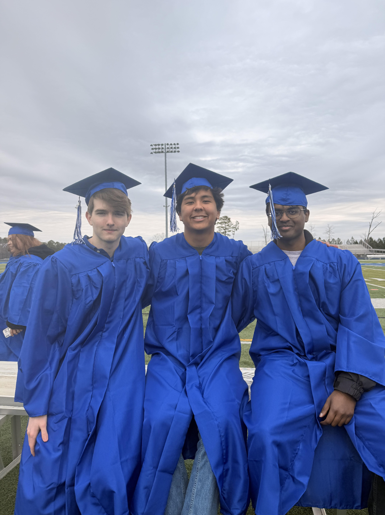 Maxwell Shealy, Liam Hogan, Akhilan Kumaran (all ‘26) ordered from left to right, sit on the Spartan Park field during graduation pictures. (Photo by Bailey Rowles (‘26))
